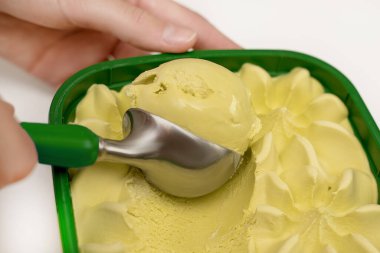 Bir kepçe taze şam fıstıklı dondurma, fıstıklı, nane elmalı ve limonlu genç bir kızın ellerinde. Mutfak aletleri kavramı, güzel bir hayat. Yakın plan fotoğraf.