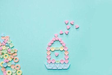 Yumuşak mavi arka planda kalpleri olan şekerden yapılmış tatlı bir ev. Yeni doğan çocuğun doğum gününü kutlarım. Mutlu aile, aşk evde yaşar. İlişkilerin psikolojisi. Ev kredisi. Uzayı kopyala Düz yatıyordu.
