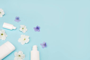 Zarif çiçek mavisi arkaplan üzerine yazı yazmak için boş yeri olan beyaz şişeler, maket. Kozmetik, krem, losyon, yüz bakımı, kaplıca, masaj, fotokopi alanı, düz yatak