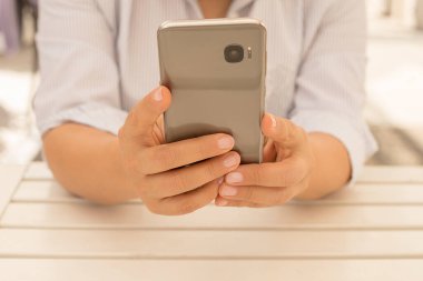 Kadınların cep telefonlu iş kadınlarının kahve molası sırasında kafedeki odunluk masasında mesaj yazarken çekilmiş yakın bir fotoğrafı. Cep telefonu kullanma kavramı.