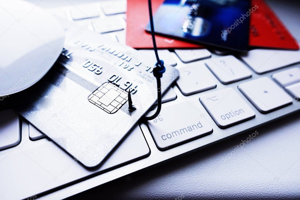 Credit card phishing attack concept, stealing credit card details with fishing hook on laptop keyboard