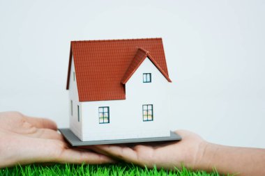Arka plan olarak mavi gökyüzü ile bir çocuk için bir model ev kahverengi çatı ile veren yetişkin