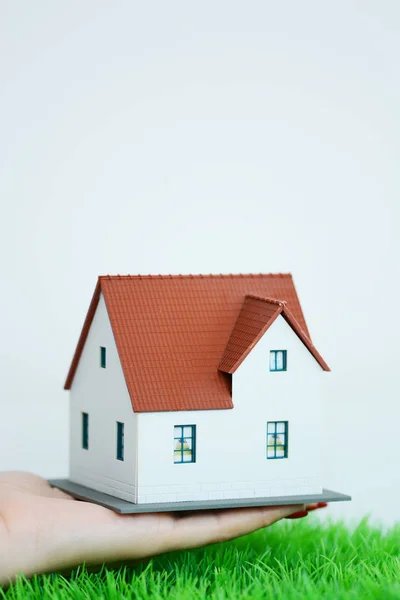 Μεσιτικό Γραφείο Κρατώντας Μικρό Μοντέλο Σπίτι Πάνω Από Πράσινο Γρασίδι — Φωτογραφία Αρχείου