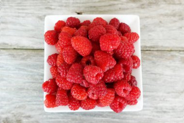 Ahşap masa veya arka plan üzerinde izole beyaz tabakta taze olgun ahududu