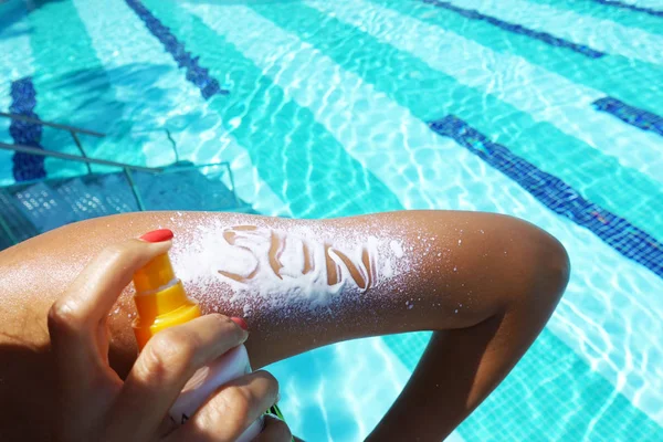 プールサイドでの女性の腕にスプレーで適用日焼け止めを日本文 — ストック写真