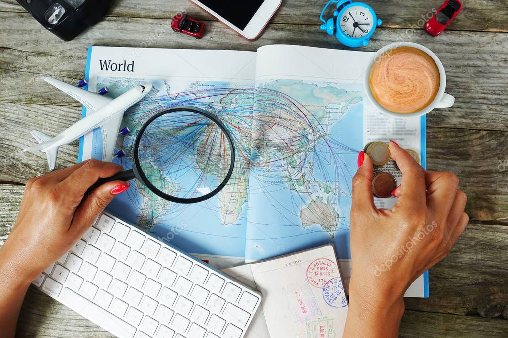 Search flight tickets online with woman looking for travel destination on map surrounded by travel objects