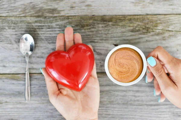 木製の背景に つの赤いハートとエスプレッソ コーヒーの一杯を保持している女性の手と愛情のこもったコーヒー概念 — ストック写真