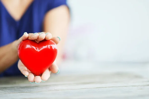 若い女の手 チャリティ コンセプトに光沢のある赤い心臓のクローズ アップ — ストック写真