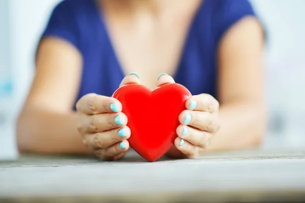 若い女の手 チャリティ コンセプトに光沢のある赤い心臓のクローズ アップ — ストック写真