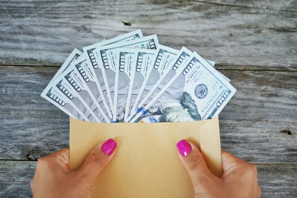 一个拿着装满美元钞票的信封的女人的手 — 图库照片