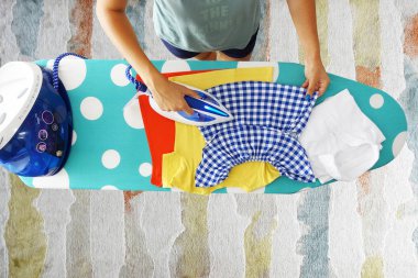 Ütü tahtasında buhar ile çocuk giysileri ütüleme kadın havadan görünümü