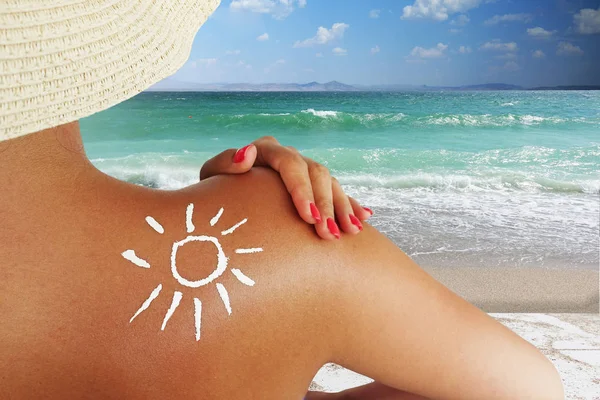 年轻女子在海滩上保护自己的皮肤 背着防晒霜晒太阳 — 图库照片