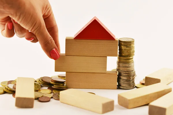 Risk of investing money in real estate projects, conceptual image with house shape from wooden blocks and cash money on white background