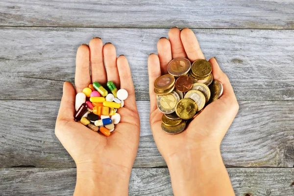 Medical expenses concept with pills and cash money in patients hands against wooden table