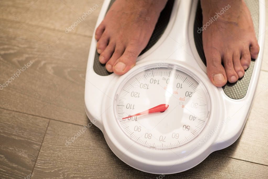 Obese or overweight male on weigh scale