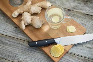 Zencefil kökü, limon, sıcak su ve bal ahşap kesme tahtası, soğuğa karşı çay için sağlıklı maddeler