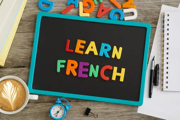 深色黑板与学习法语建议从五颜六色的塑料字母 — 图库照片
