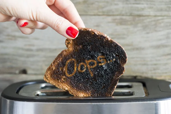 Burned toasted slice of bread in womans hand
