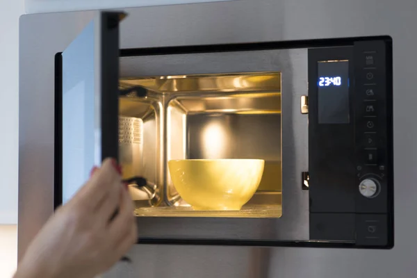 Woman at home heating food at microwave oven