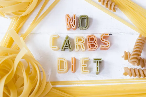 배경에 다채로운 파스타로 쓰여진 탄수화물 다이어트 텍스트 — 스톡 사진