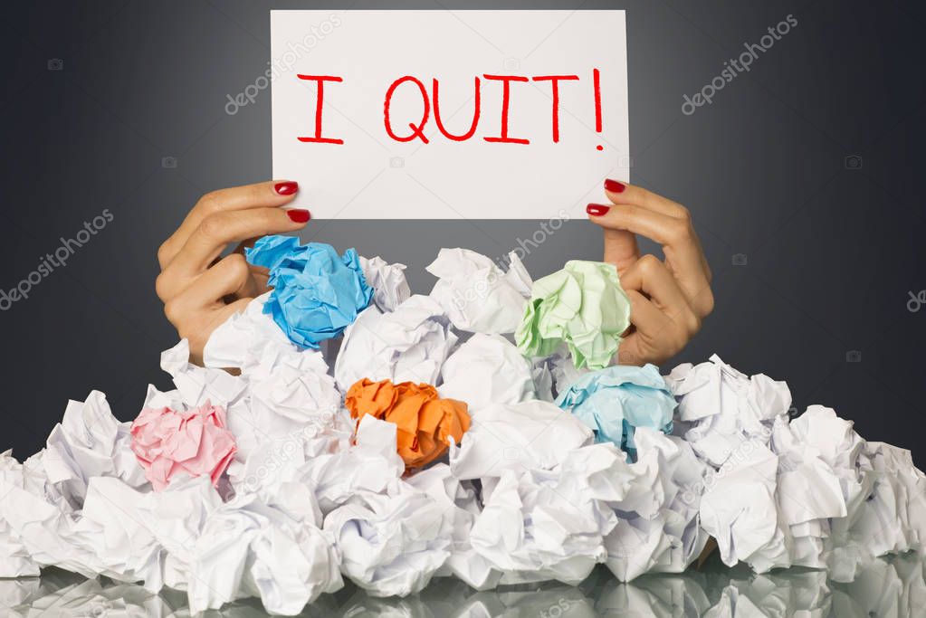 I quit, decision of exhausted employee on white paper, behind  a stack of wastepaper