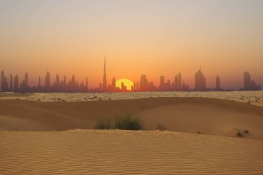 Arap Çölü'nden görülen gün batımında Dubai silueti veya şehir silueti