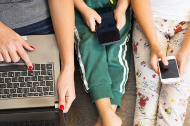 Evde akıllı telefon ve dizüstü bilgisayar olarak kablosuz teknolojiyi kullanan anne ve çocuklar