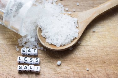 Ahşap doğrama tahtası üzerinde plastik harfler ve granül tuz ile daha az tuz tavsiye yiyin 