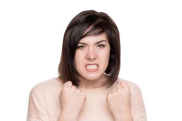 Giovane bruna furiosa su uno sfondo bianco isolato. emozioni negative di una donna. donna arrabbiata stringe le mani nei pugni — Foto Stock