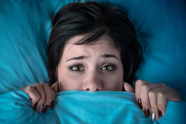 女の子は顔をベッドのカバーの下に隠してる。ホラー映画を見た後の悪夢。悪夢への恐怖 — ストック写真