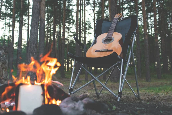 camping in the woods. man plays the guitar by the fire in nature. summer camping. relaxation in nature