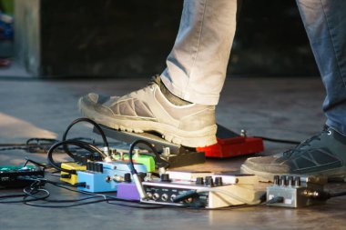 Gitarist gitarı akort ediyor. Bir konserde pedal çevirme tahtası. Gitar efektleri