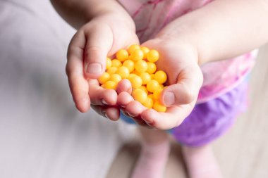 Açık çocuğun avucuna askorbik asit damlaları. Çocuk elinde C vitamini hapları tutuyor.