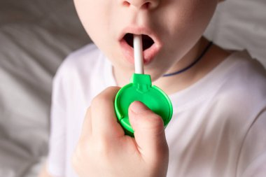 Bebek ağız spreyiyle boğaz ağrısı için ilaç alıyor.