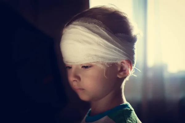 包帯頭を持つ子供 頭部外傷を負った就学前の少年 幼少期のトラウマ 未就学児の頭皮の解剖 — ストック写真