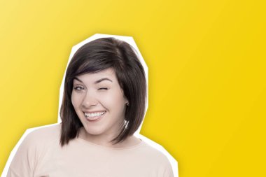 Kadın gülümsüyor ve göz kırpıyor. Sarı arka planda tatlı esmer