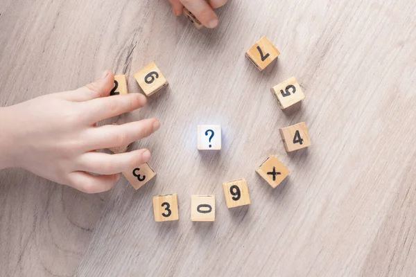 Wooden cubes with numbers. Teaching a child of preschool age mathematics. question mark. child learns numbers
