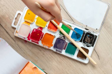 Beyaz kağıda fırça çizen çocuk eli. Çocuk üst görünümü çiziyor