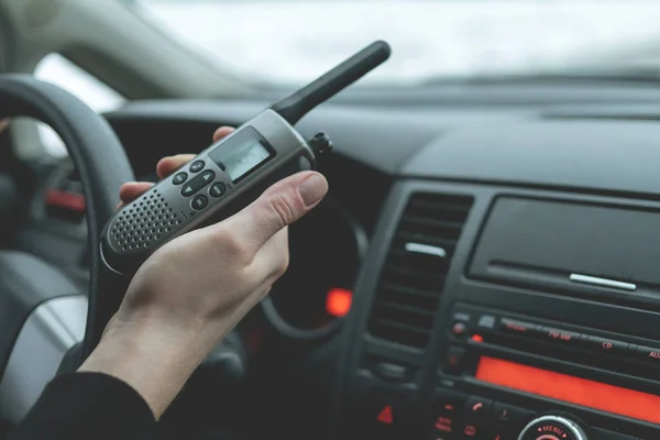 car radio station in the driver\'s hand. a man drives a car and communicates on the radio. long-distance car travel