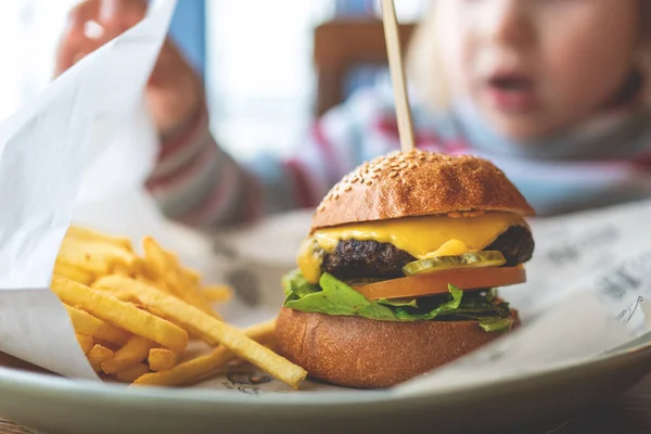 child eats a mini Burger and fries. children\'s menu in the cafe