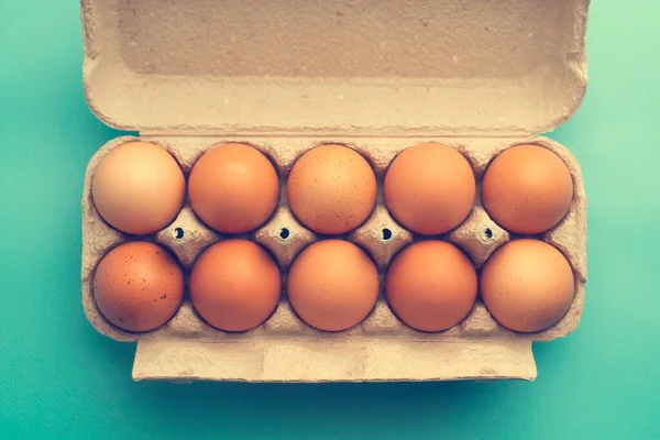 Fresh brown chicken eggs in a package on a blue background
