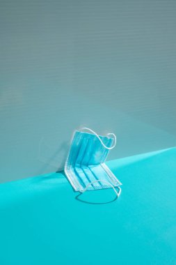 Mavi arka planda, koyu gölgeli koruyucu tıbbi maske. asgari kavram