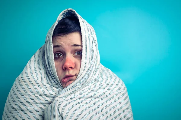 a girl with a red nose is warming herself under a blanket from a cold. antipyretic for the flu. people get sick