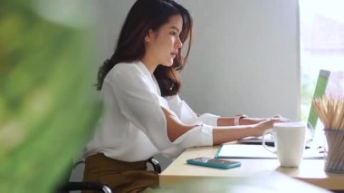 Ofiste çalışan genç bir kadın. Çekici bir ofis çalışanı masada oturuyor. İş kadını ofiste dizüstü bilgisayarda çalışmakla meşgul..