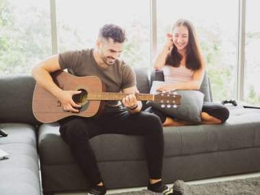Genç çift evde gitar çalmayı, evde kalmayı, Corona virüsünü, Covid-19 'u seviyor.