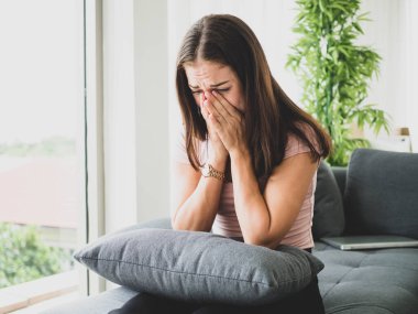 Genç, çekici ve üzgün bir kadın depresif bir şekilde evinde oturuyor endişeli ve hayal kırıklığına uğramış depresyon sorunu yaşıyor yalnız üzgün bir kadın ve odasında ağlıyor..