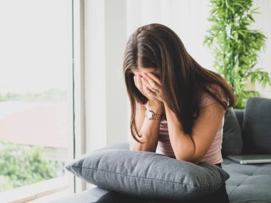Genç, çekici ve üzgün bir kadın depresif bir şekilde evinde oturuyor endişeli ve hayal kırıklığına uğramış depresyon sorunu yaşıyor yalnız üzgün bir kadın ve odasında ağlıyor..