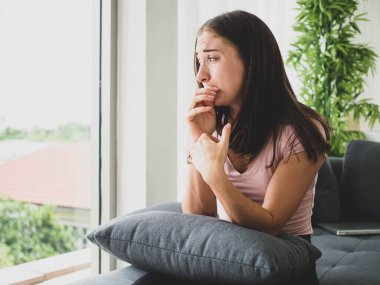 Genç, çekici ve üzgün bir kadın depresif bir şekilde evinde oturuyor endişeli ve hayal kırıklığına uğramış depresyon sorunu yaşıyor yalnız üzgün bir kadın ve odasında ağlıyor..