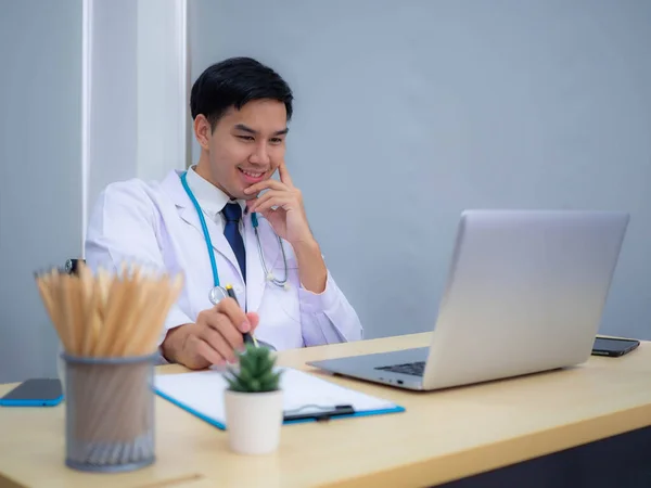 Doctor working in the office, Professional medical doctor sitting at desk in white uniform working in office.