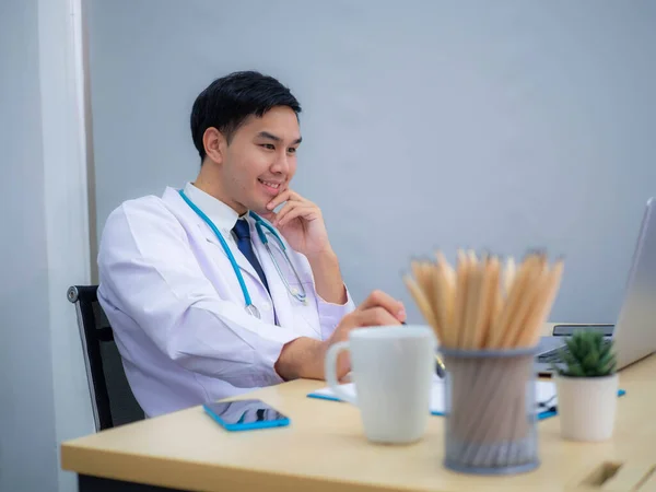 Doctor working in the office, Professional medical doctor sitting at desk in white uniform working in office.